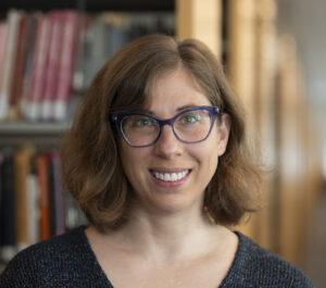 headshot of Jill Cirasella standing in front of library bookcases